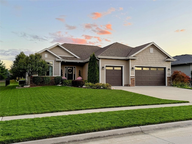 craftsman house with a shingled roof, a front yard, concrete driveway, and an attached garage