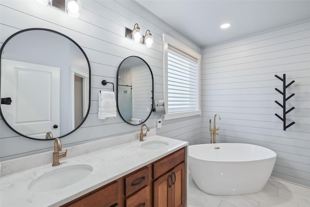 bathroom featuring double vanity, a freestanding tub, a sink, and wood walls