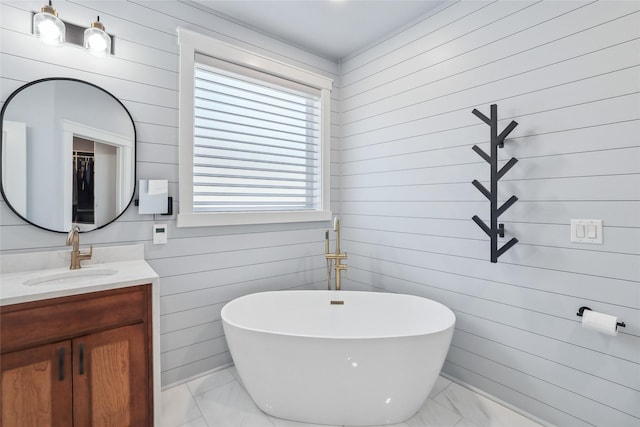 bathroom featuring wooden walls, marble finish floor, a freestanding bath, and vanity