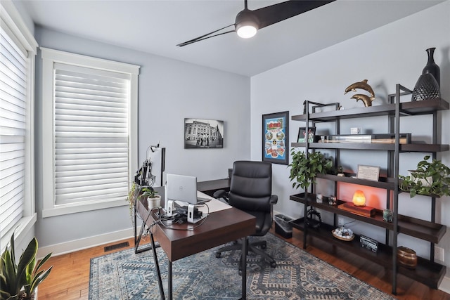 home office featuring baseboards, wood finished floors, a ceiling fan, and a healthy amount of sunlight