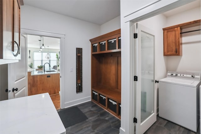 clothes washing area with cabinet space, a sink, washer / dryer, and baseboards