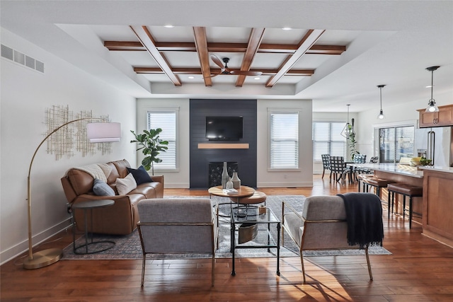 living room featuring hardwood / wood-style floors, a fireplace, coffered ceiling, and visible vents