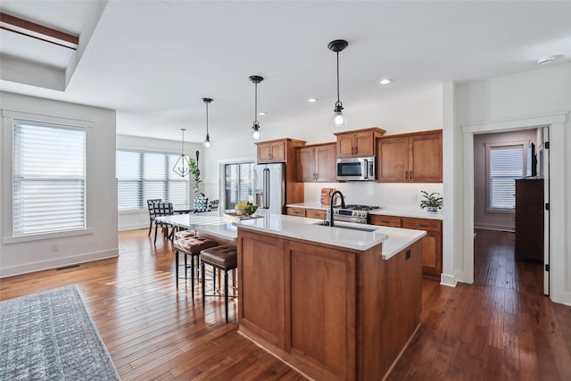 kitchen featuring visible vents, brown cabinetry, stainless steel microwave, high end fridge, and a sink