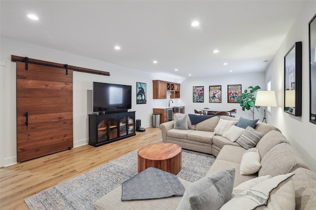 living area with recessed lighting, baseboards, light wood finished floors, and a barn door