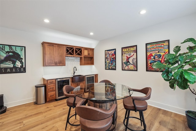 dining space featuring beverage cooler, baseboards, light wood-type flooring, indoor wet bar, and recessed lighting