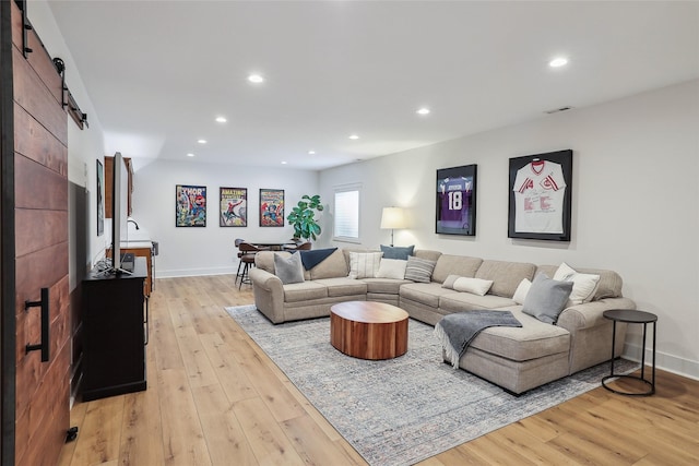 living area with light wood-type flooring, a barn door, baseboards, and recessed lighting