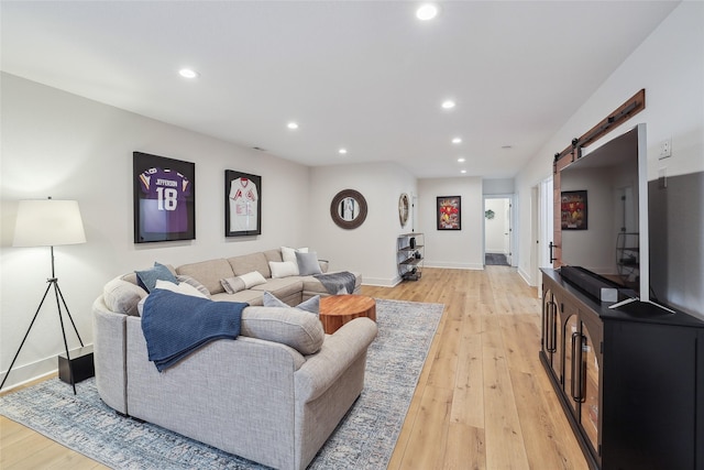 living area featuring recessed lighting, light wood-style flooring, baseboards, and a barn door