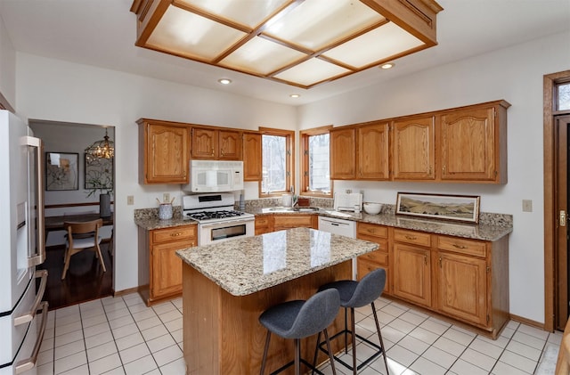 kitchen featuring white appliances, a breakfast bar, a center island, light tile patterned flooring, and recessed lighting