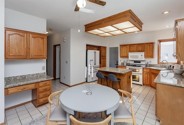 kitchen with a sink, white appliances, light tile patterned floors, and built in desk