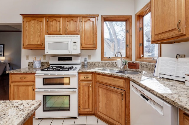 kitchen with light stone countertops, light tile patterned floors, a sink, and white appliances