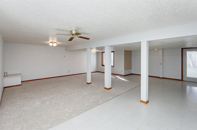 basement with light colored carpet, a textured ceiling, and baseboards