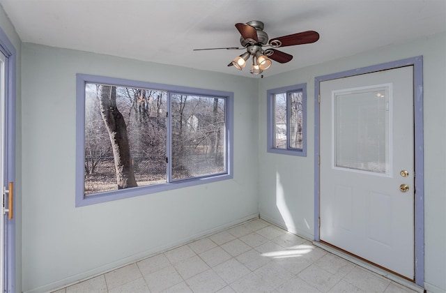 foyer entrance featuring light floors, a ceiling fan, and baseboards