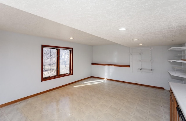 spare room featuring light floors, baseboards, a textured ceiling, and recessed lighting