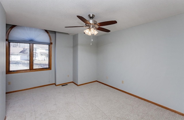 empty room featuring baseboards, visible vents, light colored carpet, ceiling fan, and a textured ceiling