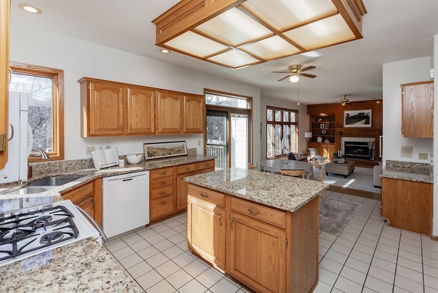 kitchen featuring a center island, light tile patterned floors, a fireplace with raised hearth, open floor plan, and dishwasher