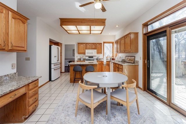 kitchen featuring light tile patterned floors, white appliances, baseboards, and a healthy amount of sunlight