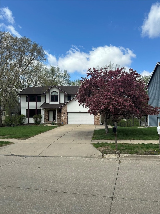 view of front facade with concrete driveway, brick siding, a front yard, and a garage