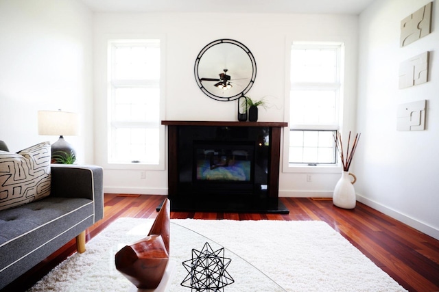 interior space featuring wood finished floors, a glass covered fireplace, and baseboards