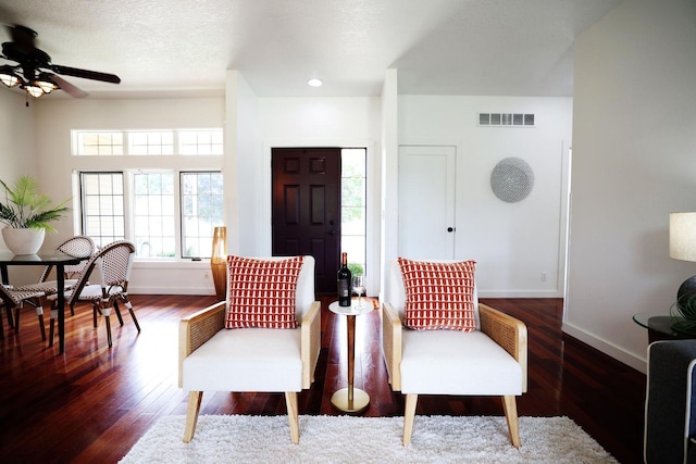 living area with visible vents, baseboards, a ceiling fan, wood-type flooring, and a textured ceiling