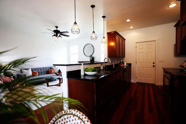 kitchen featuring recessed lighting, a peninsula, dark wood-type flooring, a sink, and open floor plan