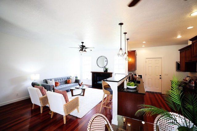 living area featuring a fireplace, baseboards, dark wood-style flooring, and recessed lighting