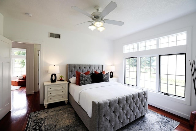 bedroom with dark wood-style flooring, visible vents, ceiling fan, a textured ceiling, and baseboards