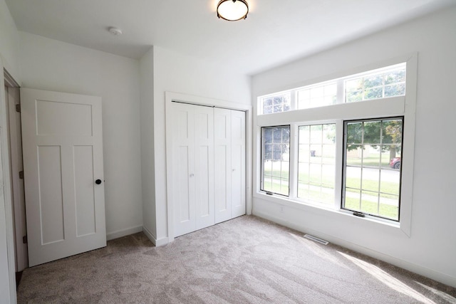 unfurnished bedroom featuring baseboards, a closet, visible vents, and carpet flooring