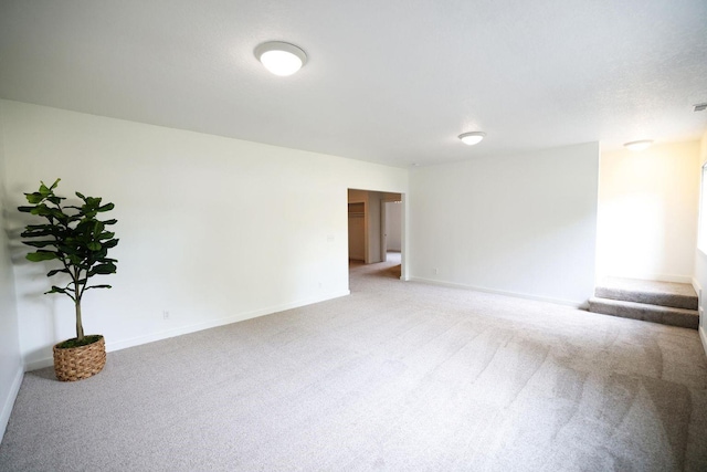 unfurnished room with stairs, baseboards, and light colored carpet