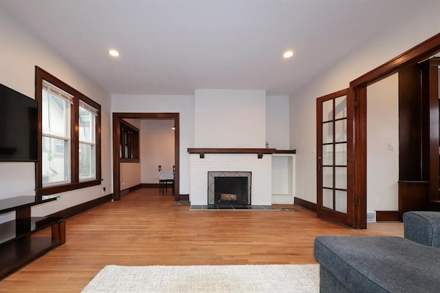 living room with light wood-style floors, a fireplace, and baseboards