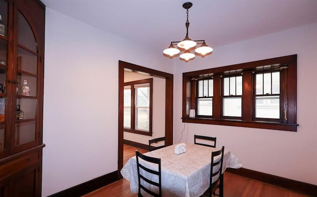 dining room with a chandelier, dark wood-style flooring, and baseboards