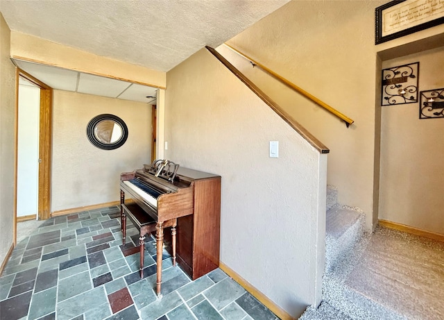 sitting room featuring stairs and baseboards