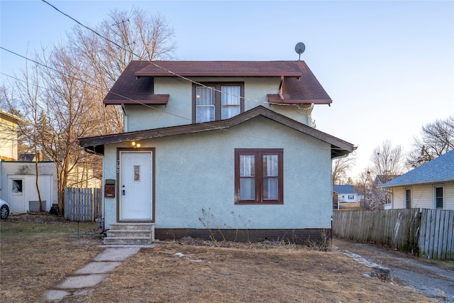 view of front of home with entry steps, fence, and stucco siding