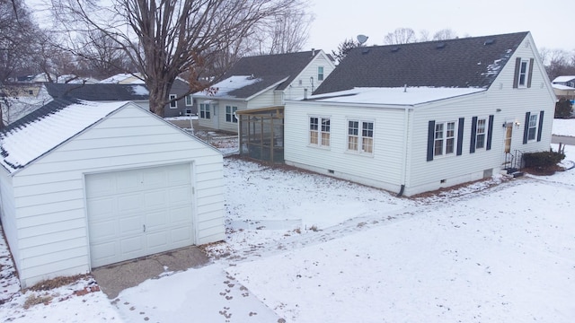 exterior space featuring a detached garage, a shingled roof, a sunroom, crawl space, and an outdoor structure