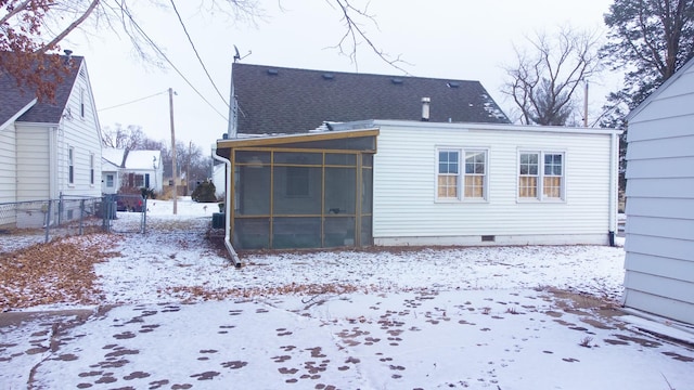 snow covered rear of property featuring a shingled roof, a sunroom, fence, and crawl space