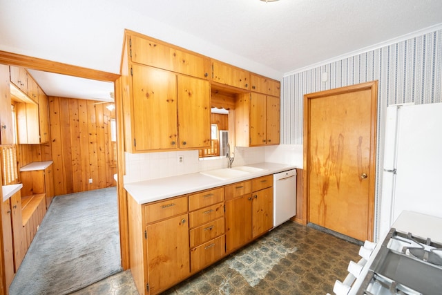 kitchen with dark floors, white appliances, a sink, light countertops, and wallpapered walls