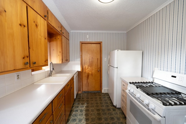 kitchen with white appliances, wallpapered walls, light countertops, a textured ceiling, and a sink