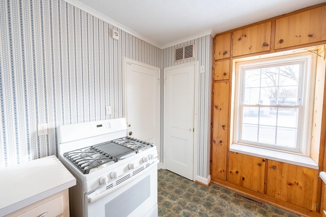 kitchen with white range with gas stovetop, visible vents, light countertops, ornamental molding, and wallpapered walls