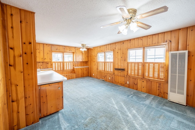 interior space featuring a textured ceiling, a ceiling fan, and wooden walls