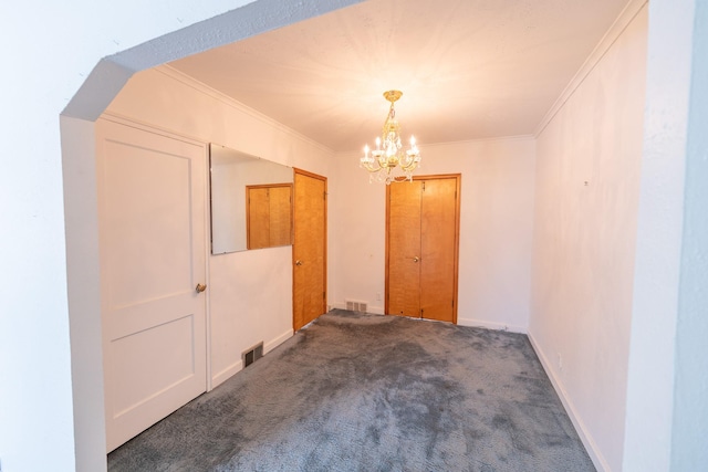 carpeted spare room with baseboards, visible vents, a chandelier, and ornamental molding