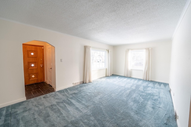 carpeted spare room with arched walkways, a textured ceiling, visible vents, and crown molding