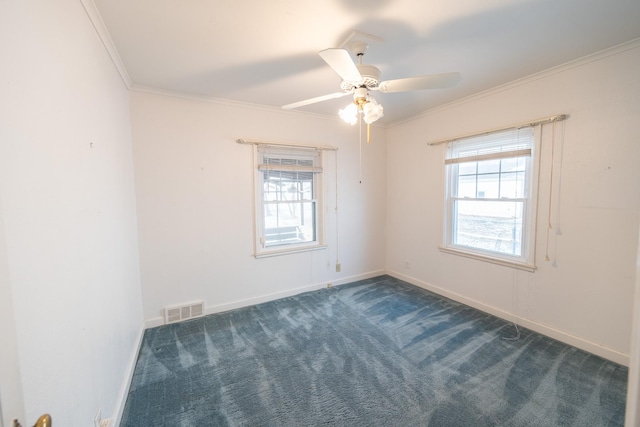 spare room with a wealth of natural light, visible vents, dark carpet, and crown molding