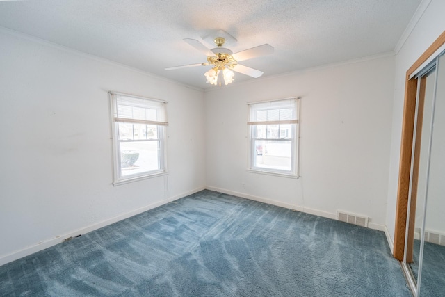 unfurnished bedroom featuring carpet floors, ornamental molding, multiple windows, and visible vents