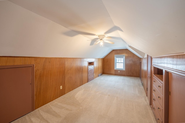 bonus room with lofted ceiling, wooden walls, and light colored carpet