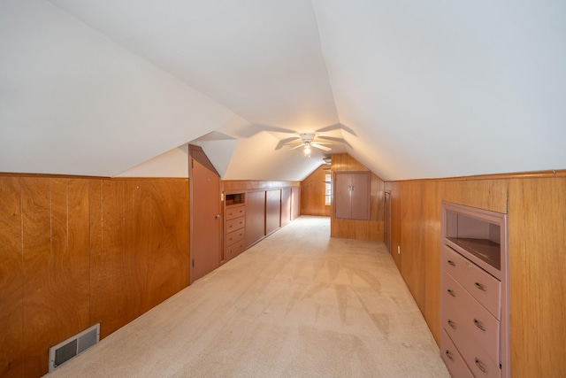 additional living space with light carpet, lofted ceiling, visible vents, and wooden walls