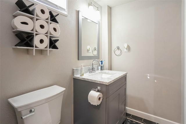 half bath featuring toilet, baseboards, and vanity