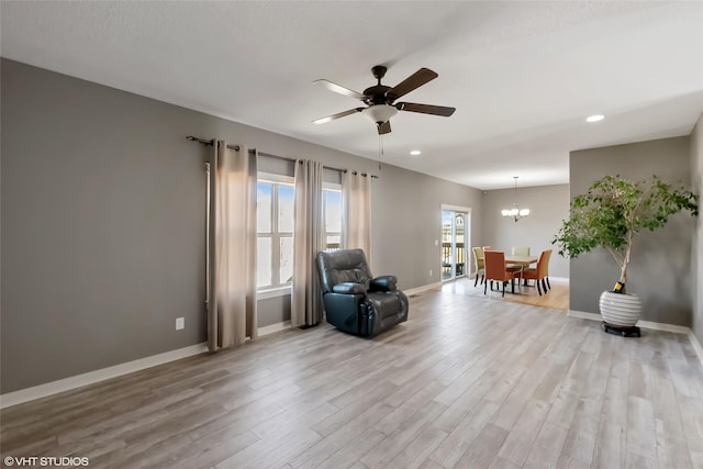 sitting room featuring ceiling fan with notable chandelier, recessed lighting, wood finished floors, and baseboards