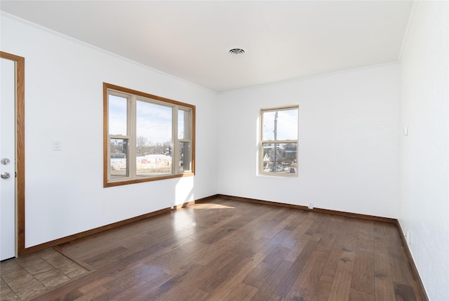 spare room with ornamental molding, visible vents, baseboards, and wood finished floors