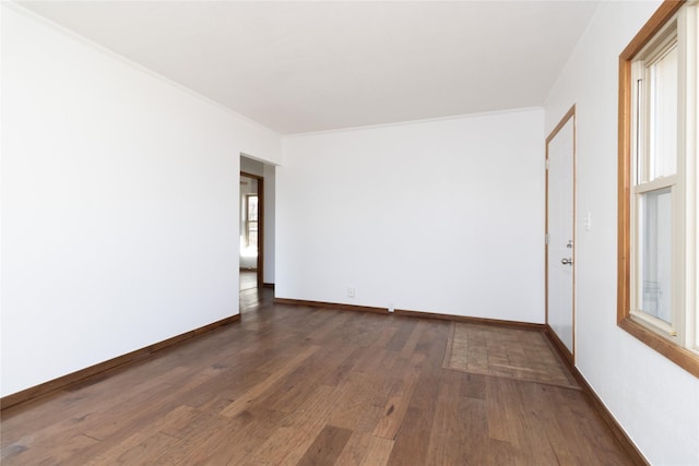 unfurnished room featuring crown molding, baseboards, and wood finished floors