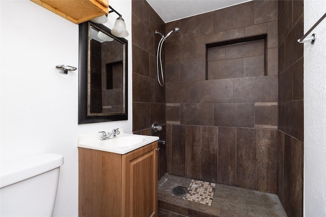 full bath featuring toilet, tiled shower, and vanity