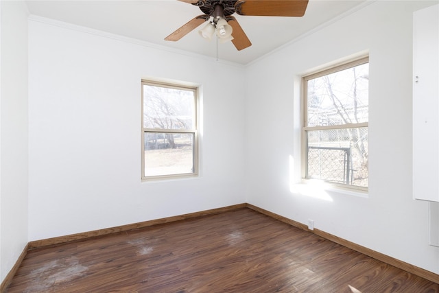 empty room with a ceiling fan, baseboards, dark wood finished floors, and crown molding